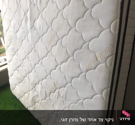 מזרן עומד על דשא מלאכותי, נראה נקי ומסודר
